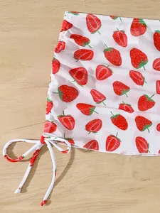 Detail view of girls' white mesh swimwear featuring a vibrant strawberry print pattern