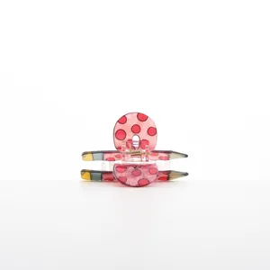 Close-up of a creative pink pencil-shaped hair claw clip with red polka dots