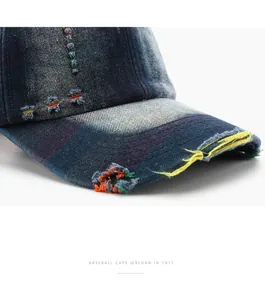Macro detail of distressed washed denim baseball cap with frayed edges and colorful stitching