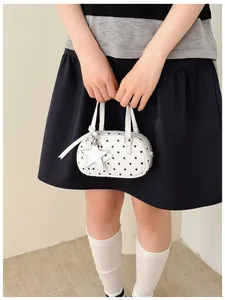Model holding white polka dot bowling bag with star charm detail and top handles