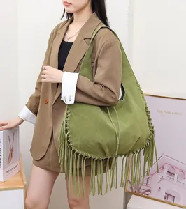 Detailed macro view of green suede hobo bag featuring long tassels and whipstitch detailing