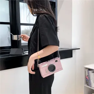 Detailed view of a creative pink camera-shaped crossbody box bag worn by a model