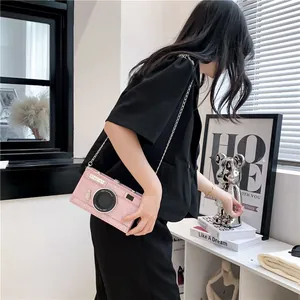Detailed view of stylish pink camera-shaped box bag with silver chain strap on model