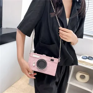 Chic pink camera-shaped box bag with glitter finish and chain strap on female model