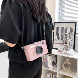 Close-up of a stylish pink camera shaped crossbody box bag with silver chain strap