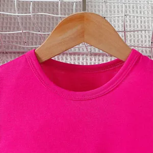 Detail of fuchsia pink round neck girls' cotton t-shirt displayed on a wooden hanger