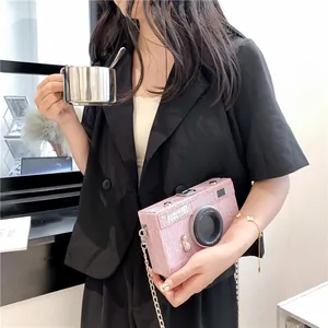 Detail of pink camera-shaped box bag held by model wearing a black blazer