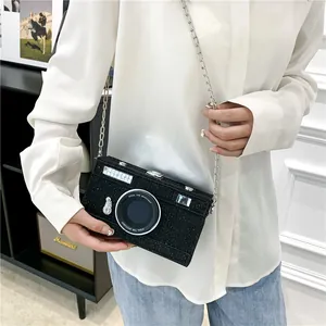 Close-up detail of a unique black glitter camera-shaped box bag with silver chain strap