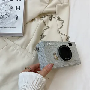 Detail of a creative silver camera-shaped box bag with glitter finish and chain strap