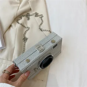 Close-up of a creative silver glitter camera-shaped box bag with a metallic chain strap