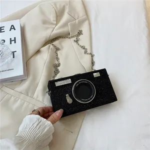Close-up of a stylish black glitter camera-shaped box bag with chain strap.