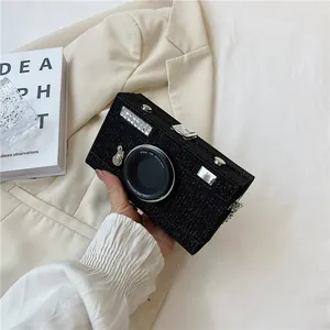 Detail of creative camera-shaped box bag with black glitter finish and silver hardware.
