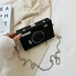 Detailed view of a black glitter camera-shaped box bag with a silver chain strap