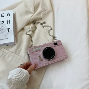 Detail of a pink rhinestone camera-shaped crossbody bag with a silver chain strap