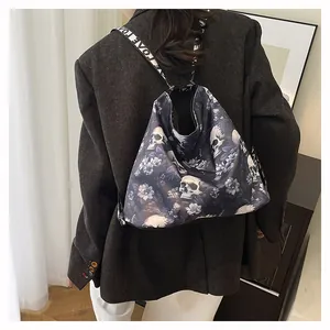 Rear view detail of a large tote bag with skull and floral print worn by a model