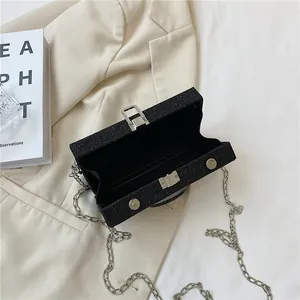 Detail shot of a black glittery camera box bag showing the open interior and silver chain