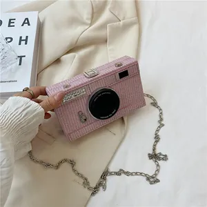 Close-up of pink tweed camera-shaped crossbody bag with rhinestone details