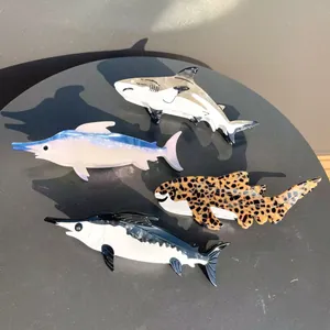 Detailed view of ocean-themed acetate hair claw clips in shark and fish shapes.