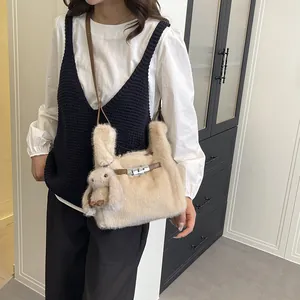 Detail view of a cute beige faux fur handbag with a rabbit doll charm accessory