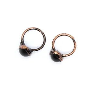 Macro detail of two vintage copper-tone open rings featuring smooth black stone cabochons.