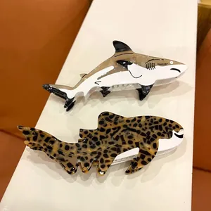 Close-up detail of cute acetate shark and leopard print hair claw clips in warm light
