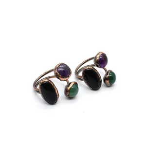 Close-up of antique bronze adjustable rings with black, purple, and green stones.