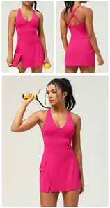Detailed view of hot pink one-piece tennis dress featuring cross-back straps and side slit