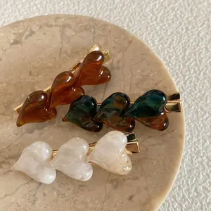 Vintage heart-shaped hair clips featuring three resin charms on gold duckbill clips