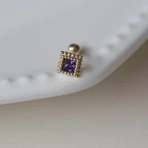 Vue macro d'une boucle d'oreille en zircon violet carré avec cadre élégant plaqué or 18 carats