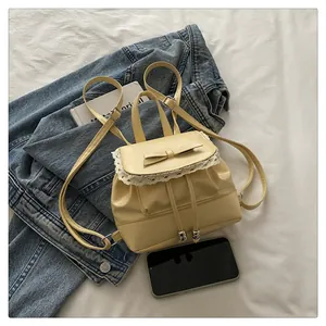 Detail of a cream lace bow mini backpack on a denim jacket background