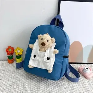 Gros plan d'un sac à dos bleu pour enfant avec une poche en peluche en forme d'ours.