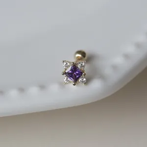 Gros plan d'une boucle d'oreille en or avec zircon violet carré et pierres