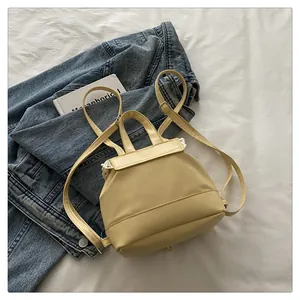 Top-down view of a cream PU leather mini backpack with delicate lace trim on denim.