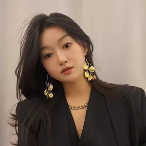 Elegant vintage gold-toned metal leaf drop earrings with long design shown on female model