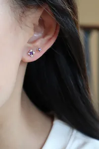 Boucles d'oreilles élégantes en argent doré avec zircon violet sur l'oreille du mannequin