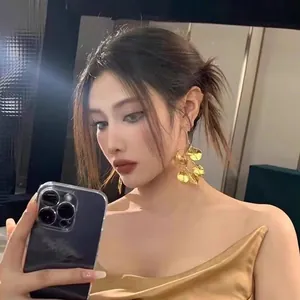 Exaggerated retro metallic gold leaf drop earrings for women shown on model in mirror selfie
