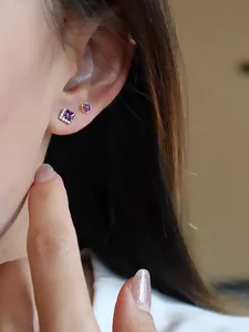 Gros plan détaillé montrant des boucles d'oreilles en zircon violet sur l'oreille