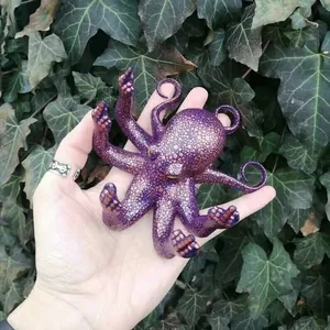 Macro detail of purple resin octopus figurine with orange spots held against ivy