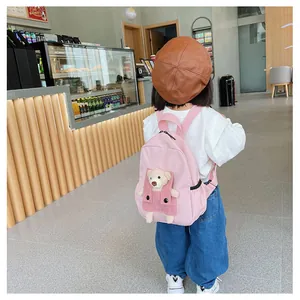 Vue d'un sac à dos rose pour enfant avec un petit ours en peluche dans la poche