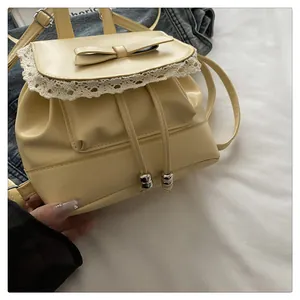 Close-up detail of yellow oily leather backpack with white lace trim and bow accent