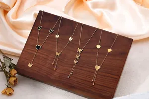 Elegant gold butterfly and heart necklaces displayed on a professional wooden display stand