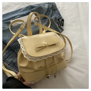 Detail view of a cream faux leather backpack with cute bow and delicate lace trim
