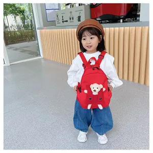 Adorable petite fille portant un sac à dos rouge de maternelle avec un ours en peluche