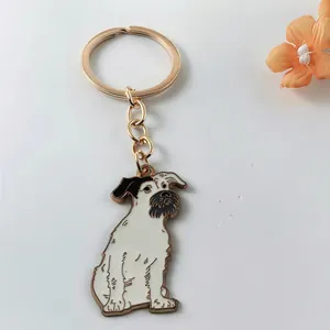 Close-up of a gold dog keychain featuring a cute white and black schnauzer pendant.