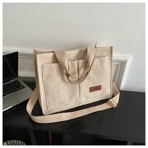 Beige corduroy tote bag with multiple pockets and adjustable shoulder strap.