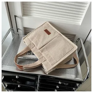 Close-up of cream corduroy tote bag with fashion patch on industrial trolley background