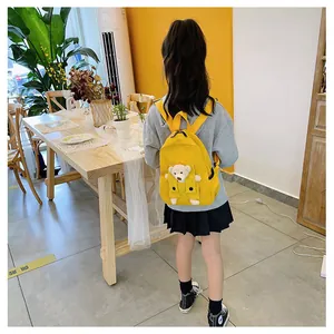Vue arrière d'un enfant portant un sac à dos ours jaune mignon dans un café lumineux