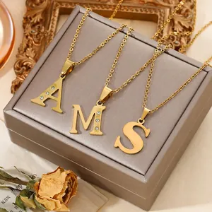 Close-up of gold titanium steel initial necklaces A M S with crystal accents
