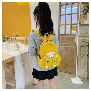 Joli sac à dos jaune pour enfants avec un petit ours en peluche, vue de dos en situation.