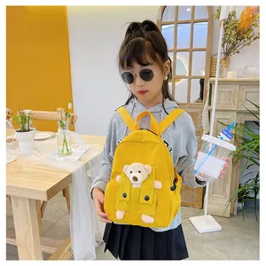 Détail d'un sac à dos jaune pour enfants avec mascotte ours en peluche 3D
